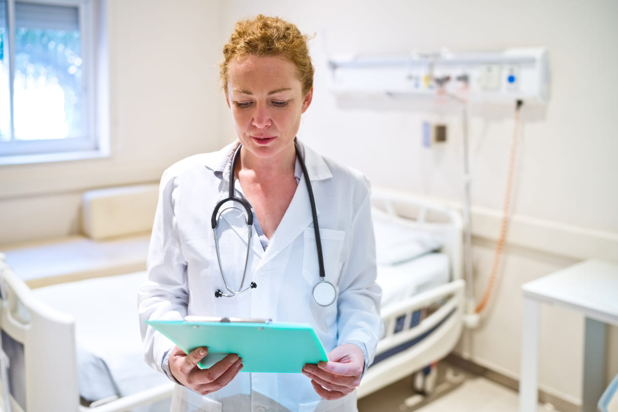 Mature female doctor reading clipboard while working in hospital